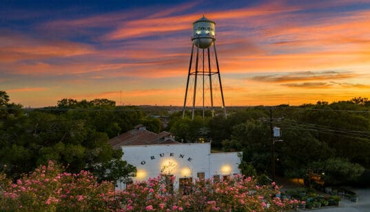 Gruene Hall and Gruene water tower beneath a colorful sunset in New Braunfels, Texas.