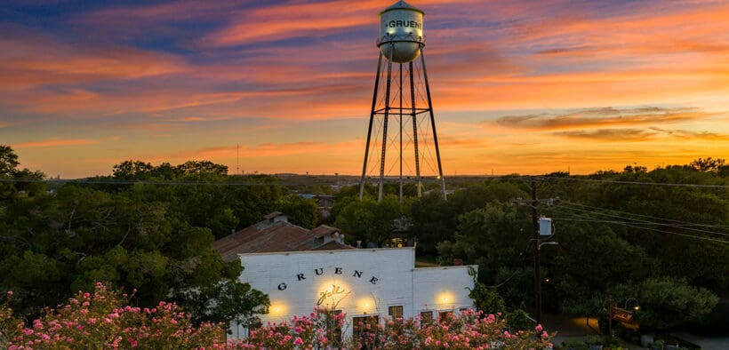 Gruene Hall and Gruene water tower beneath a colorful sunset in New Braunfels, Texas.