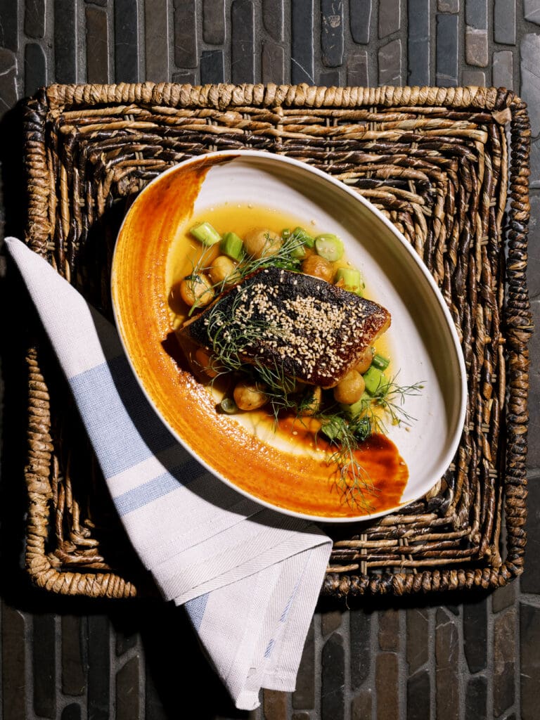 Plated fish with sesame seeds, vegetables, herbs and sauce at Urban Hill in Salt Lake City