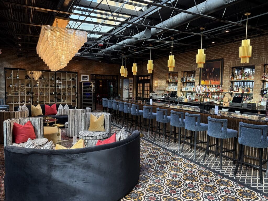 Bar and lounge at The Faust Hotel featuring blue seating, patterned tile floors and statement lighting.