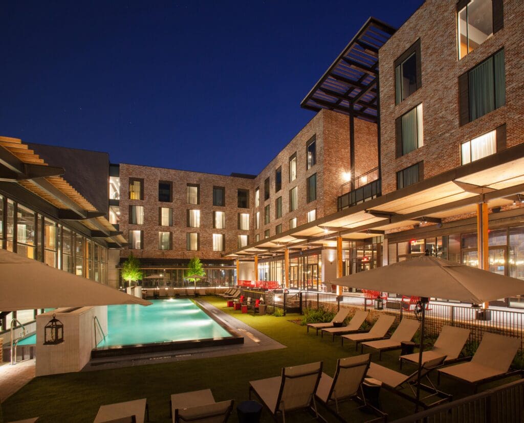 Outdoor pool and courtyard at The George hotel in College Station illuminated at night.