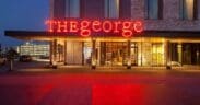 The front of The George hotel in College Station with a neon sign "THE george."