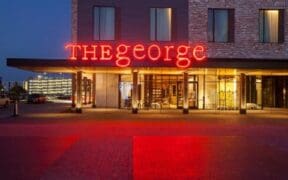 The front of The George hotel in College Station with a neon sign "THE george."