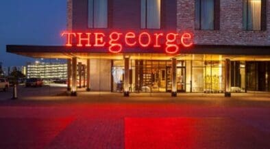 The front of The George hotel in College Station with a neon sign "THE george."