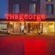 The front of The George hotel in College Station with a neon sign "THE george."