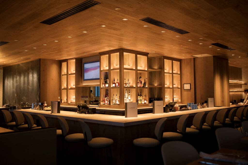 Warmly lit wood bar and seating inside Urban Hill in Salt Lake City.
