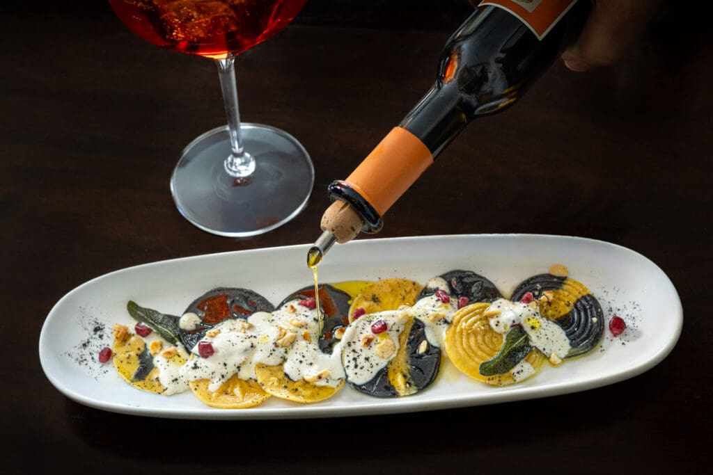 Colorful pasta finished tableside with olive oil at Virtù Honest Craft.