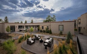 Washington Inn Santa Fe exterior with covered balconies, courtyard seating and ornamental grasses.
