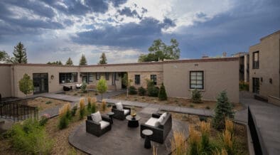 Washington Inn Santa Fe exterior with covered balconies, courtyard seating and ornamental grasses.