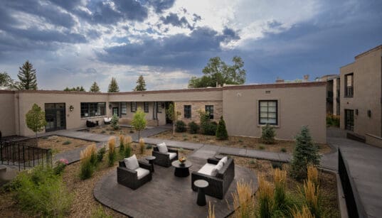 Washington Inn Santa Fe exterior with covered balconies, courtyard seating and ornamental grasses.