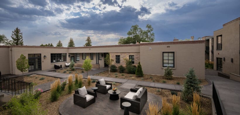 Washington Inn Santa Fe exterior with covered balconies, courtyard seating and ornamental grasses.